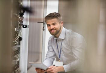 Technician using digital tablet while analyzing server